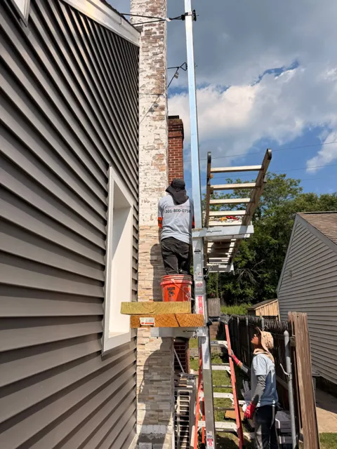 Stone veneer installation along a chimney with scaffolding