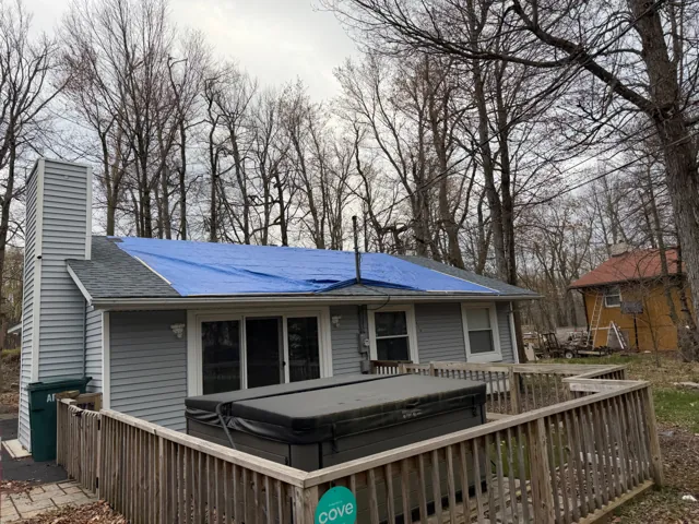 Cottage roof with blue underlayment viewed across a deck