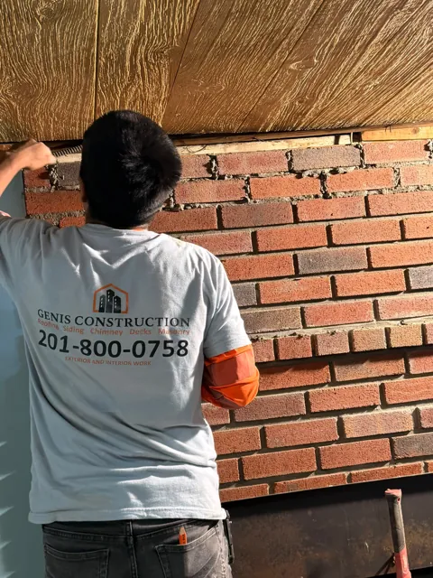 Genis team member working on brick masonry below wood framing