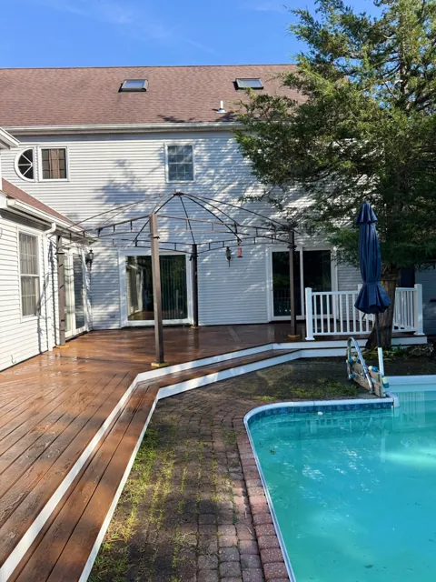 Wood deck beside a pool with a pergola frame