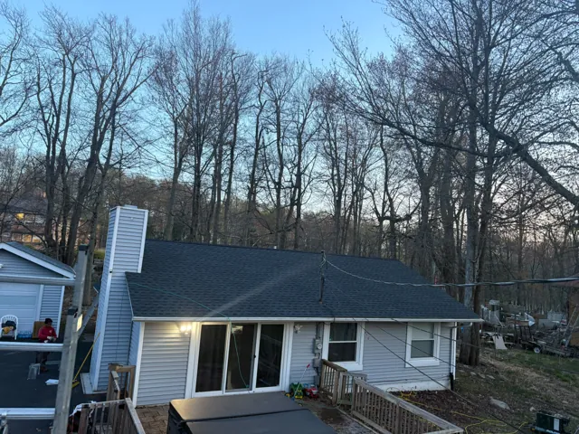 Cottage with a completed roof and warm porch lighting at dusk
