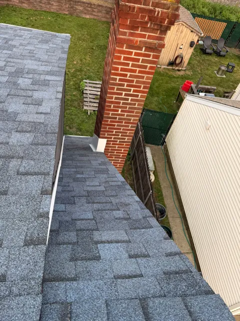 Shingle roof meeting a brick chimney with flashing